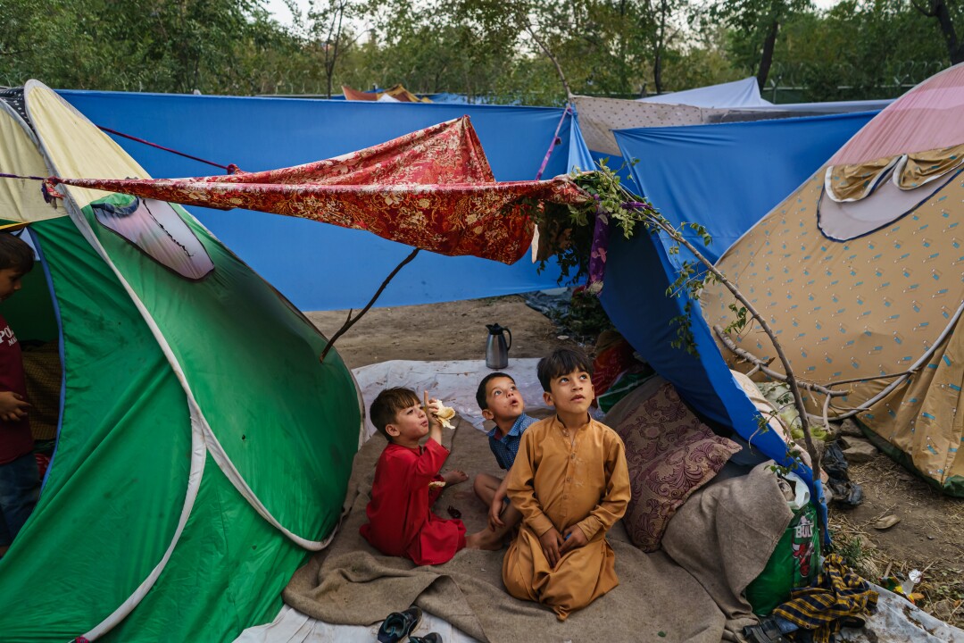 Des enfants afghans regardent un avion passer un camp de fortune