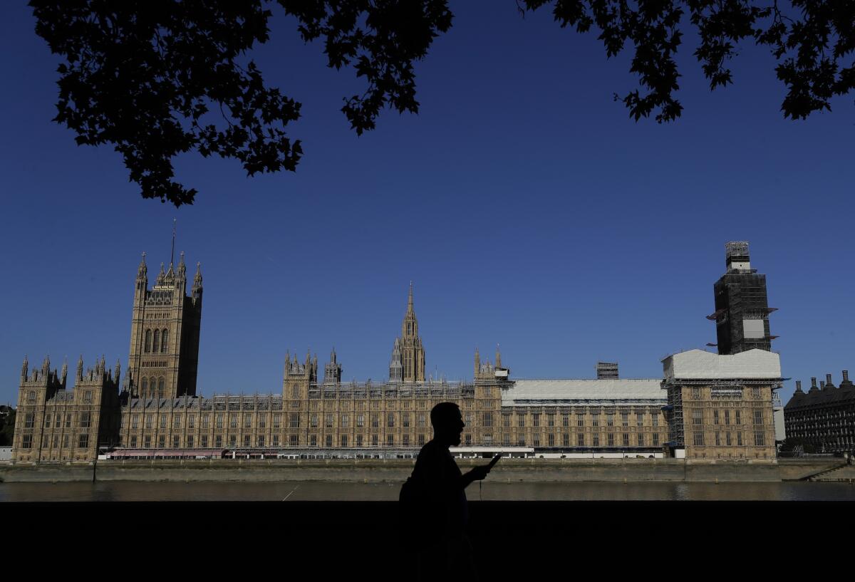 FILE - A pedestrian passes Britain's Houses of Parliament on the bank of The River Thames in London, Aug. 29, 2019. A U.K. Conservative lawmaker has been released on bail while police investigate allegations of rape and sexual assault against him. The legislator was arrested Tuesday May 17, 2022, on suspicion of indecent assault, sexual assault, rape, abuse of position of trust and misconduct in public office. (AP Photo/Kirsty Wigglesworth, File)