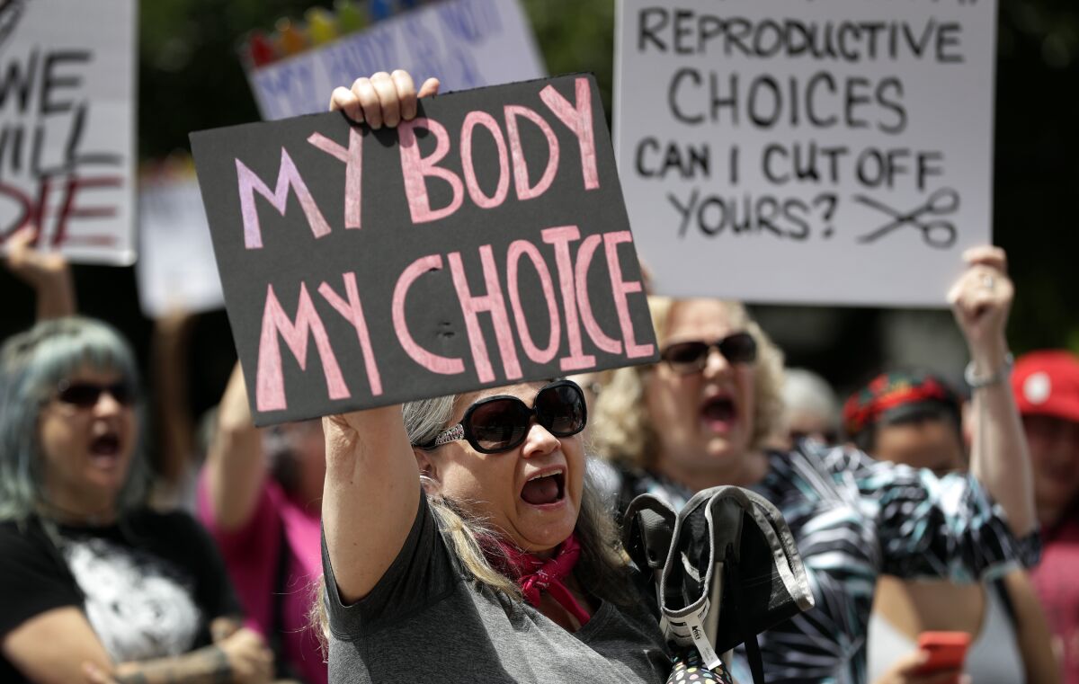 Abortion rights supporters hold signs reading "My body my choice" and "Reproductive choices can I cut off yours?"