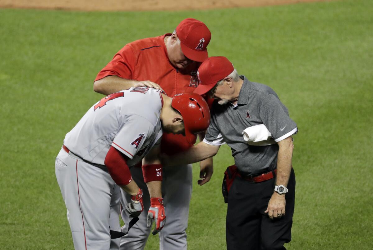 Angels first baseman C.J. Cron, left, is checked by Manager Mike Scioscia and a trainer after being hit by a pitch by Baltimore's Mike Wright on Friday.