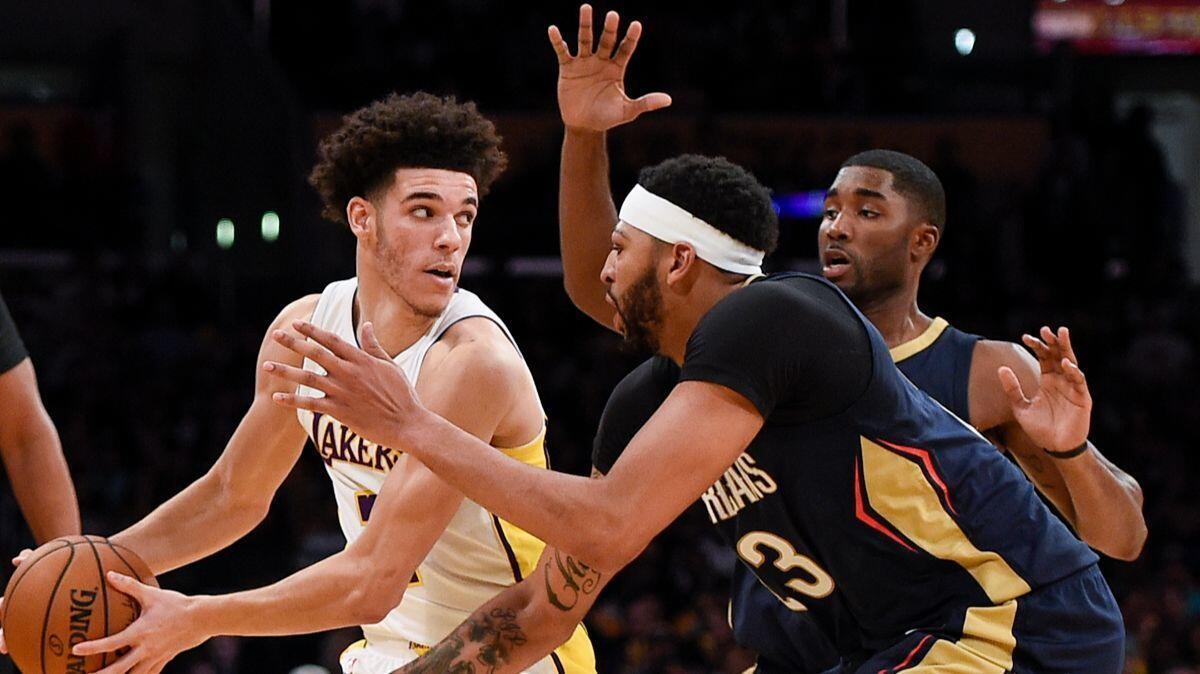 Lakers guard Lonzo Ball, left, holds the ball defended by New Orleans Pelicans forward Anthony Davis, front, and guard E'Twaun Moore during the second half on Sunday.