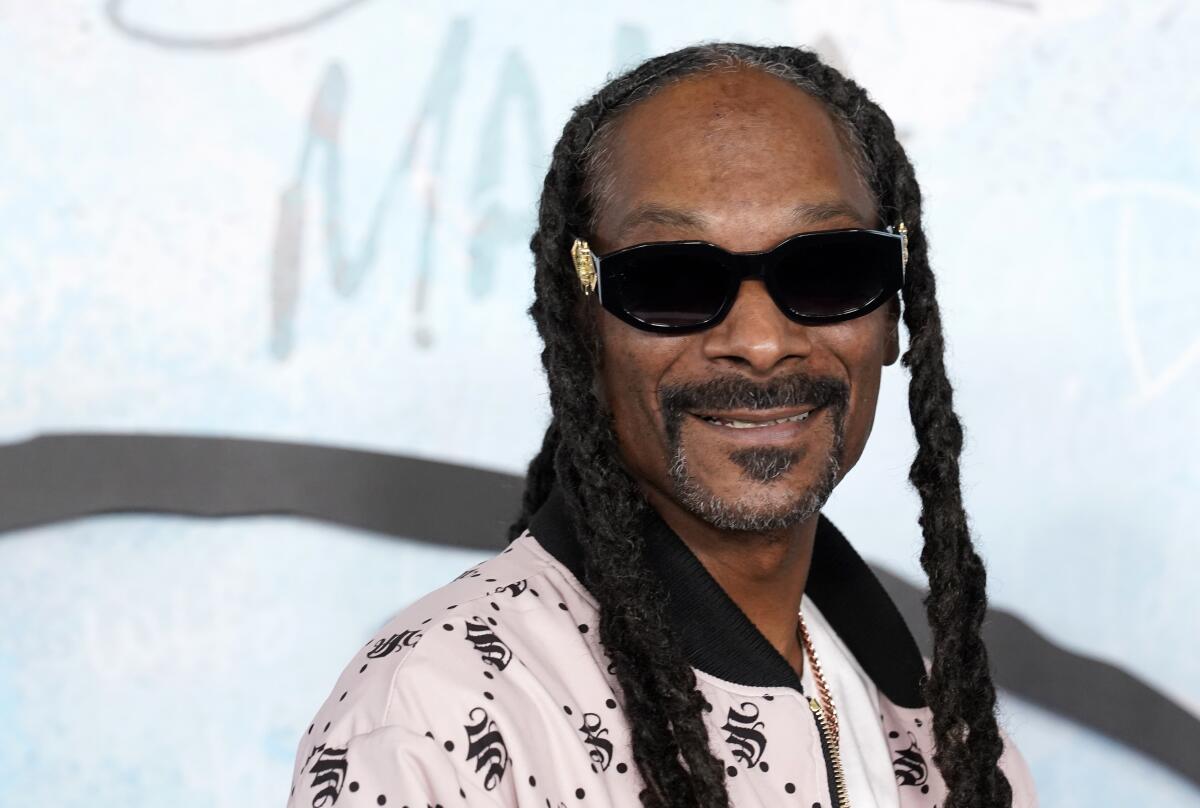 Snoop Dogg wears shades and smiles as he poses at the premiere of the FX docuseries "Dear Mama"