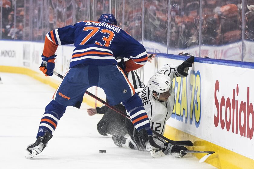 Los Angeles Kings' Trevor Moore (12) is checked by Edmonton Oilers' Vincent Desharnais (73) during the first period of an NHL hockey game Thursday, March 30, 2023, in Edmonton, Alberta. (Jason Franson/The Canadian Press via AP)
