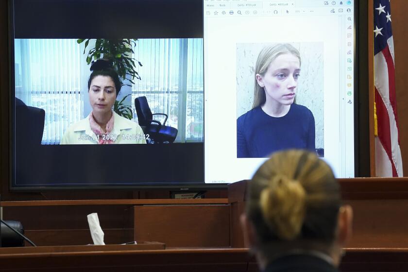 Actor Johnny Depp listens as Raquel Pennington testifies in a previously recorded video deposition, as a picture of Amber Heard is seen on screen, in the courtroom at the Fairfax County Circuit Courthouse in Fairfax, Va., Wednesday, May 18, 2022. Actor Johnny Depp sued his ex-wife Amber Heard for libel in Fairfax County Circuit Court after she wrote an op-ed piece in The Washington Post in 2018 referring to herself as a "public figure representing domestic abuse." (Kevin Lamarque/Pool Photo via AP)