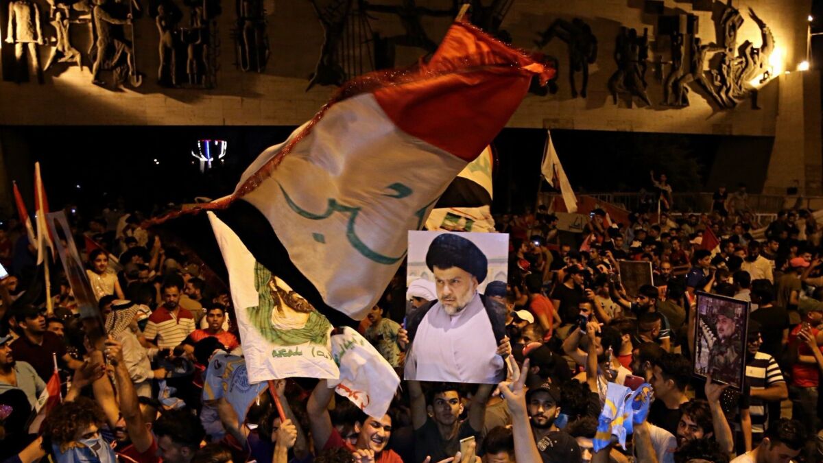 Iraqi followers of Shiite cleric Muqtada Sadr, seen in the poster, celebrate in Baghdad's Tahrir Square on May 14, 2018.
