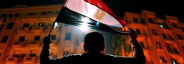 A man holds the Egyptian flag aloft in Tahrir Square after the announcement that President Hosni Mubarak would step down.