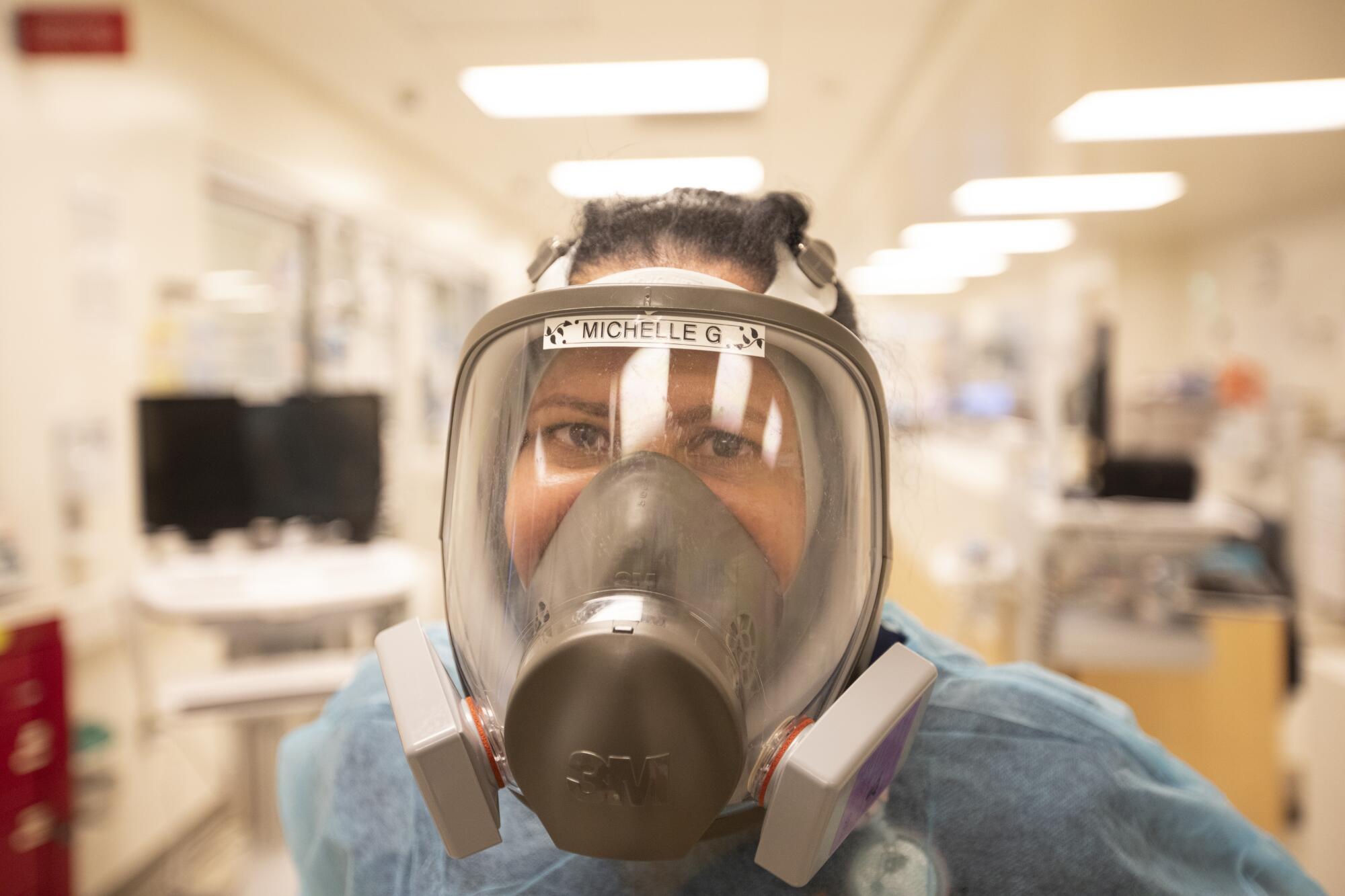 A closeup of a nurse in a respirator mask. 