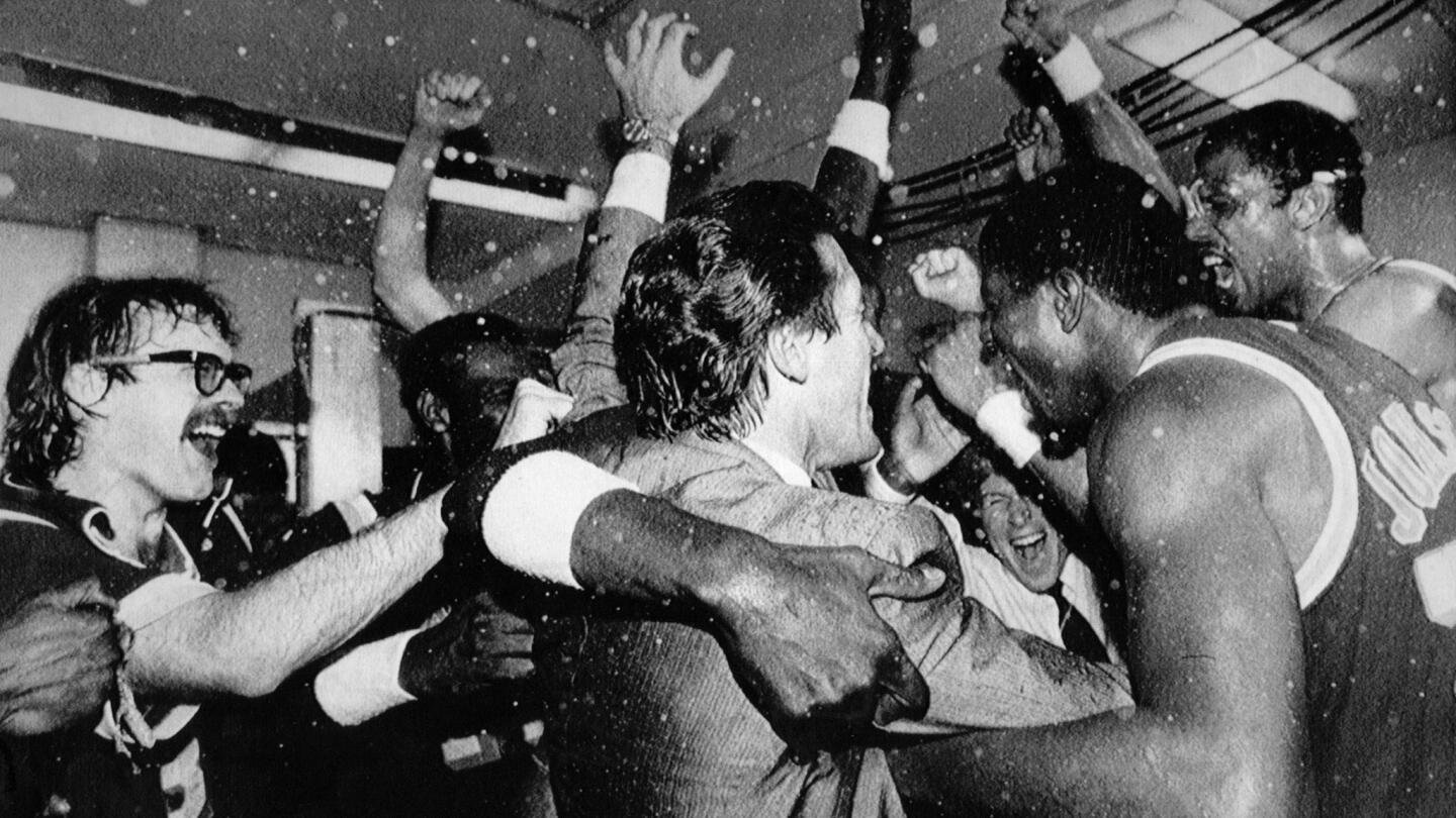 The Lakers' Kurt Rambis, left, Coach Pat Riley, center, and Magic Johnson, right, celebrate with the rest of the team in the locker room after beating the Boston Celtics in Game 6 to win the 1985 NBA Finals.