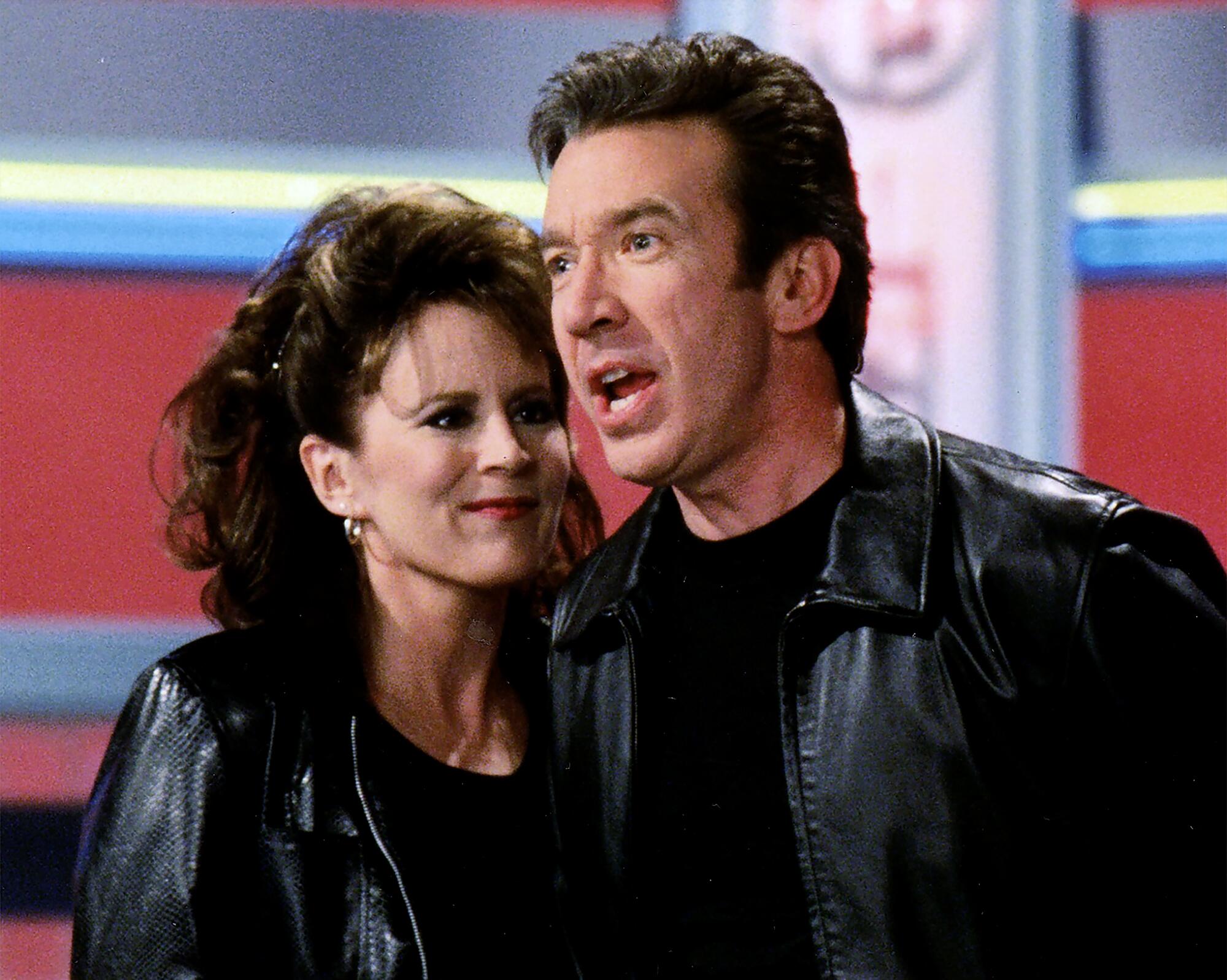 A woman and a man in dark jackets and T-shirts.