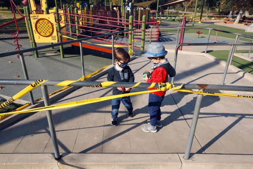 Los Angeles, CA DECEMBER 10, 2020 - Idris Solaiman, 3, left, plays with 2 year old Felix Quon, right, on the playground in Griffith Park Thursday morning, December 10, 2020. Idris' mother, Denni Kephart, and Felix's father, Jarrod Quon, met at the park for their children to play after they heard LA County playgrounds would re-open. Yellow caution tape remained up as Maintenance crews at Griffith Park said they hadn't received word yet to remove the tape.