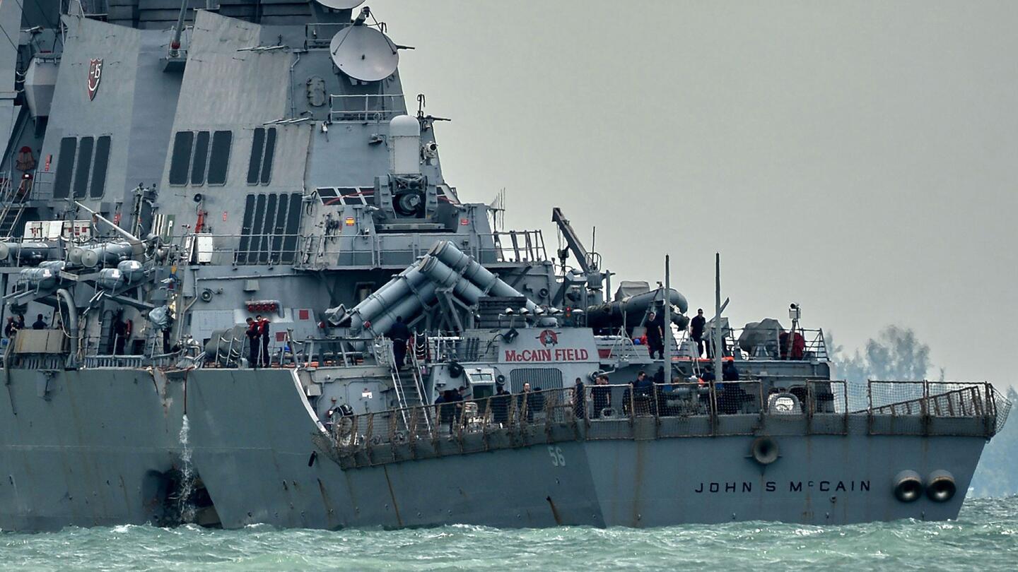 The guided-missile destroyer USS John S. McCain, with a hole on its portside after a collision with an oil tanker, makes its way to Changi naval base in Singapore on August 21, 2017.