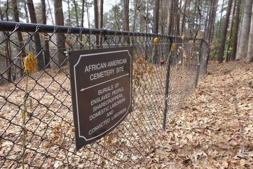 Flowers adorn a fence marking an African American cemetery site at Woodland Cemetery in Clemson, South Carolina on Sunday, Feb. 28, 2021. Students at Clemson University who found an unkempt graveyard on campus last year sparked the discovery of more than 600 unmarked graves most likely belonging to enslaved Black people, sharecroppers and convicted laborers. The revelation has Clemson working to identify the dead and properly honor them amid a national reckoning by universities about their legacies of racial injustice. (AP Photo/Michelle Liu)