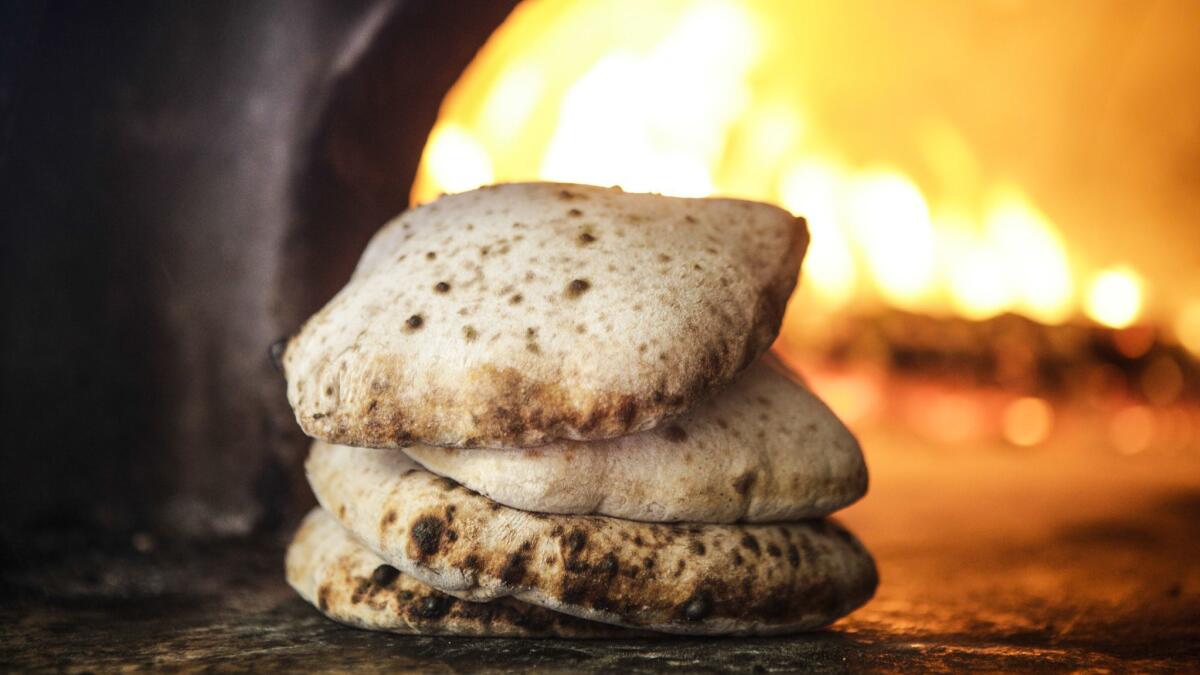 The pita flatbread puffs up in the fire oven and bakes very quickly.