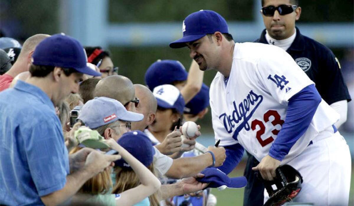 Adrian Gonzalez signs a baseball for fans before the game against the Miami Marlins on Aug. 25, 2012.