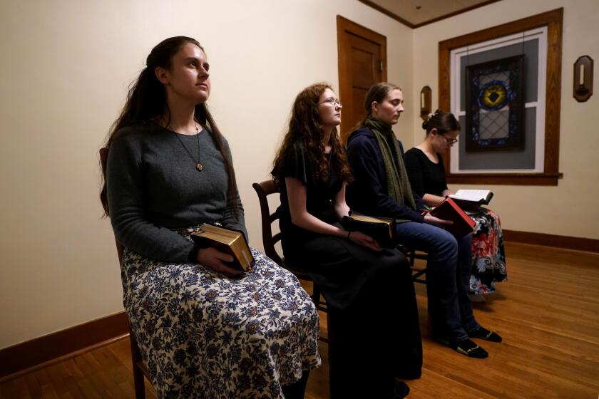 Benedictine College students, from left, Madeline Hays, Niki Wood, Ashley Lestone and Hannah Moore gather for evening prayers in a room which they converted to a chapel in the house they share Sunday, Dec. 3, 2023, in Atchison, Kan. Across the U.S., the Catholic church is undergoing an immense shift. Generations of Catholics who embraced the modernizing tide are increasingly giving way to religious conservatives who believe the church has been twisted by change. (AP Photo/Charlie Riedel)