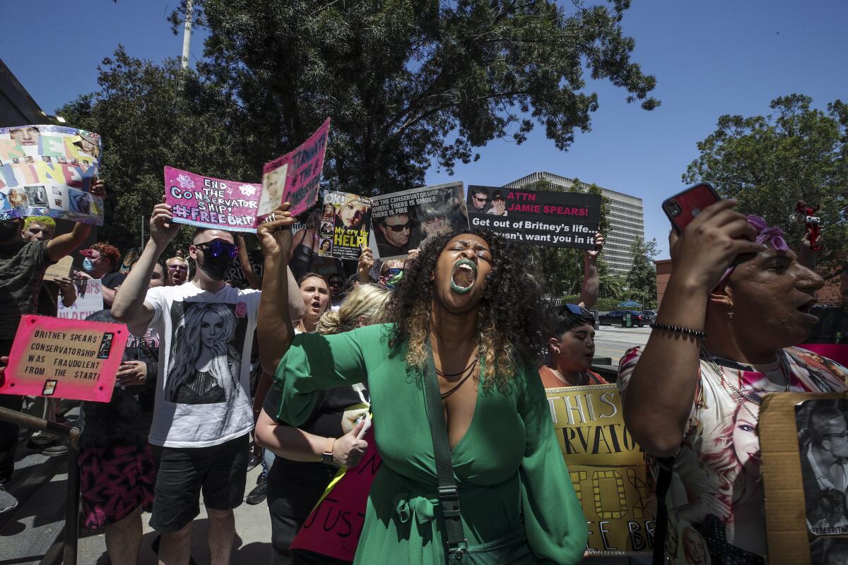 A woman in a green dress leads a crowd of protesters.