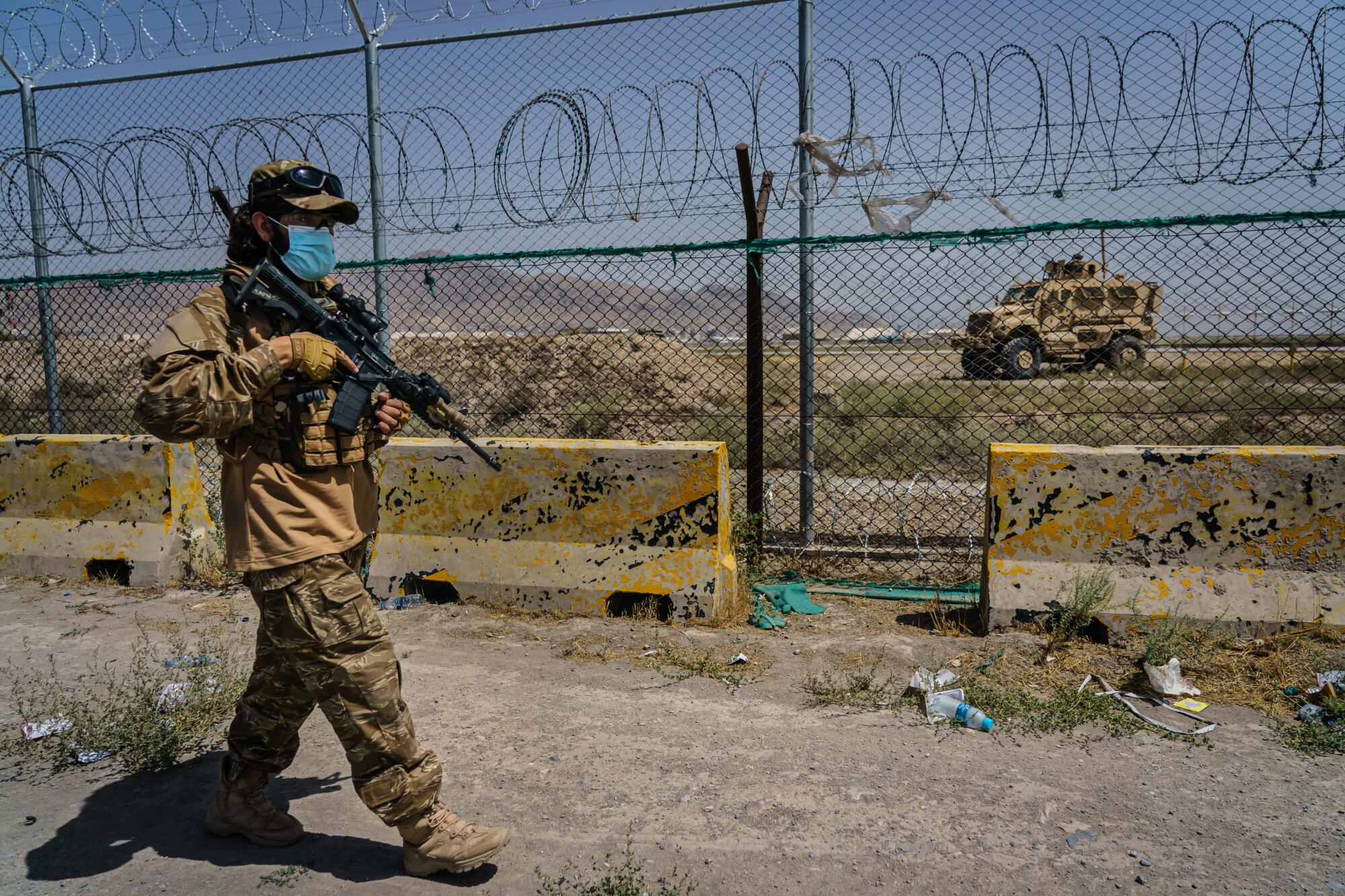 A masked man with a gun patrols outside the Kabul airport.