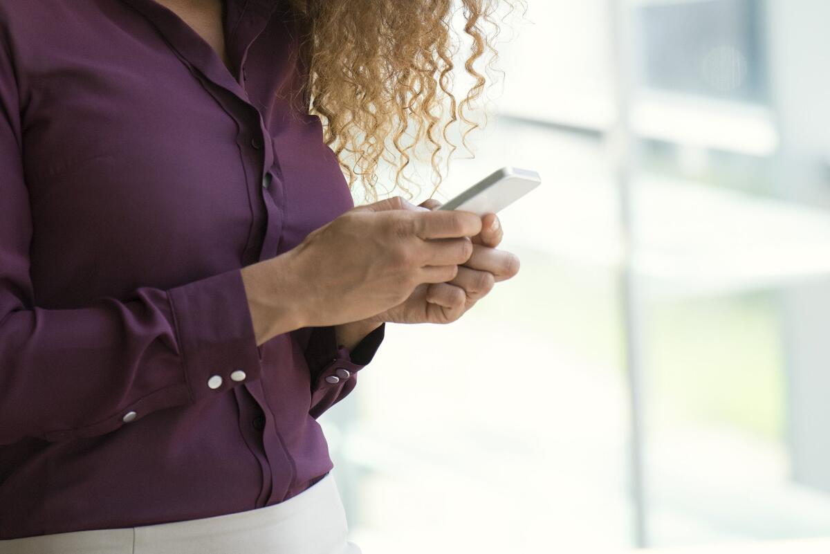 A woman uses a smartphone. The use of such devices is cutting into the time Americans spend watching TV, according to new Nielson data.