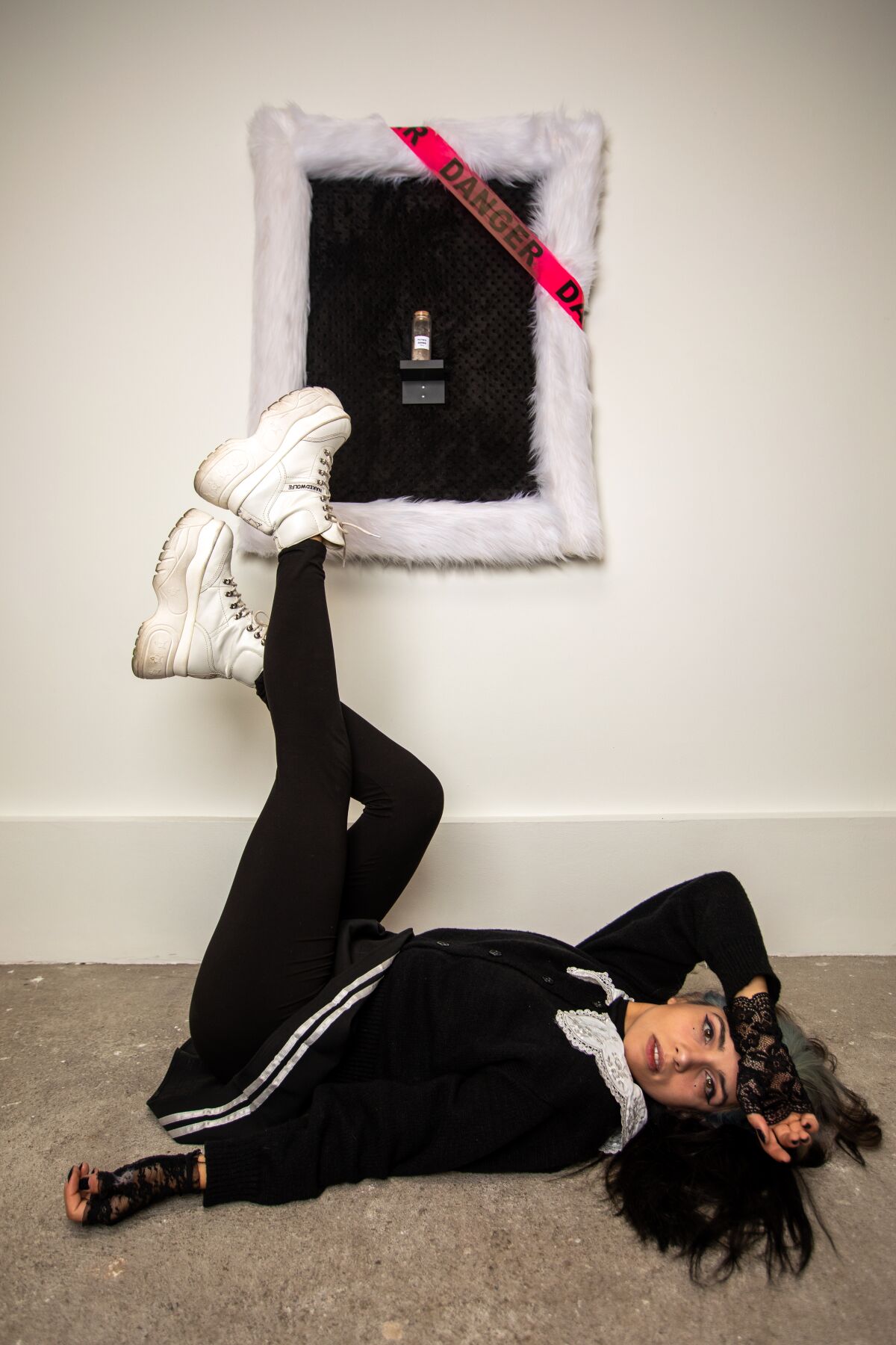 a woman with dark hair poses on a floor next to a framed artwork.