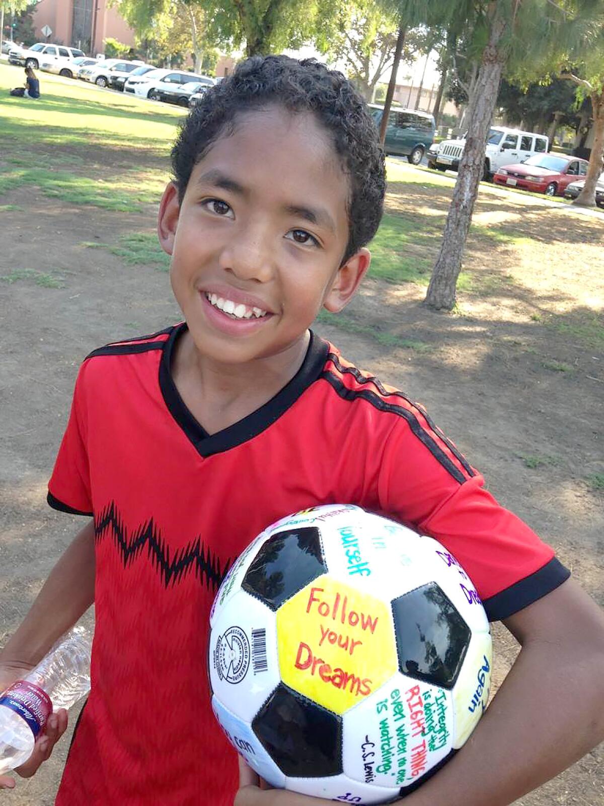 A kid in the Pure Game program holds a soccer ball. Pure Game uses soccer to mentor kids, teaching them character.