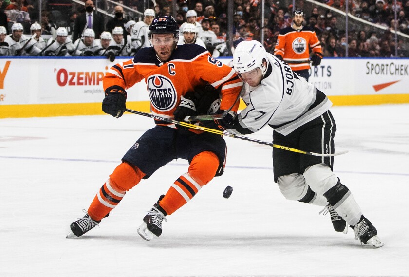 Los Angeles Kings' Tobias Bjornfot (7) and Edmonton Oilers' Connor McDavid (97) battle for the puck during the second period of an NHL hockey game in Edmonton, Alberta, Sunday, Dec. 5, 2021. (Jason Franson/The Canadian Press via AP)