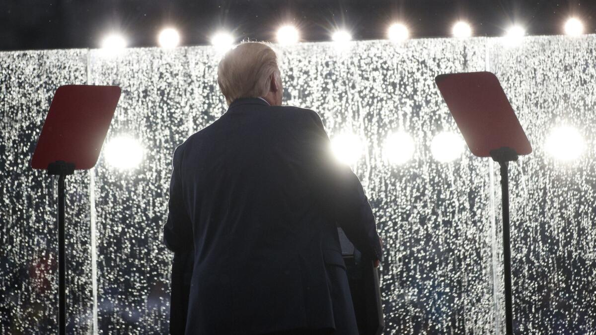 President Trump speaks in the rain behind glass during a July 4 celebration in front of the Lincoln Memorial.