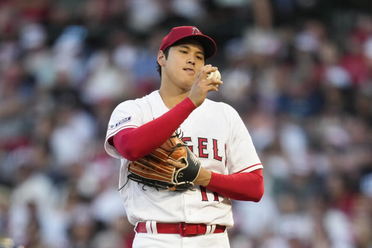 Angels starting pitcher Shohei Ohtani looks at a ball during a game.
