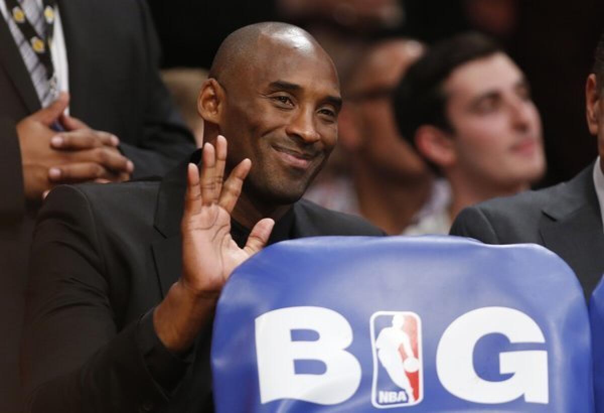 Kobe Bryant waves from behind the Lakers' bench during the team's home opener against the Clippers at Staples Center on Tuesday.