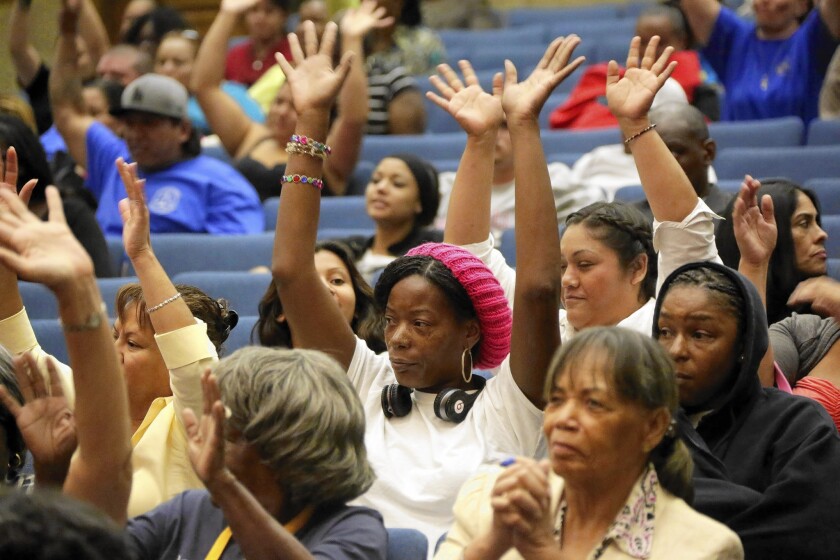 Tracy Willis, wearing a cap, and others raise their hands in support of the blue ribbon commission report on child services presented at the L.A. County Board of Supervisors meeting.
