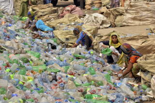 Women with head coverings sort through a massive expanse of plastic bottles.