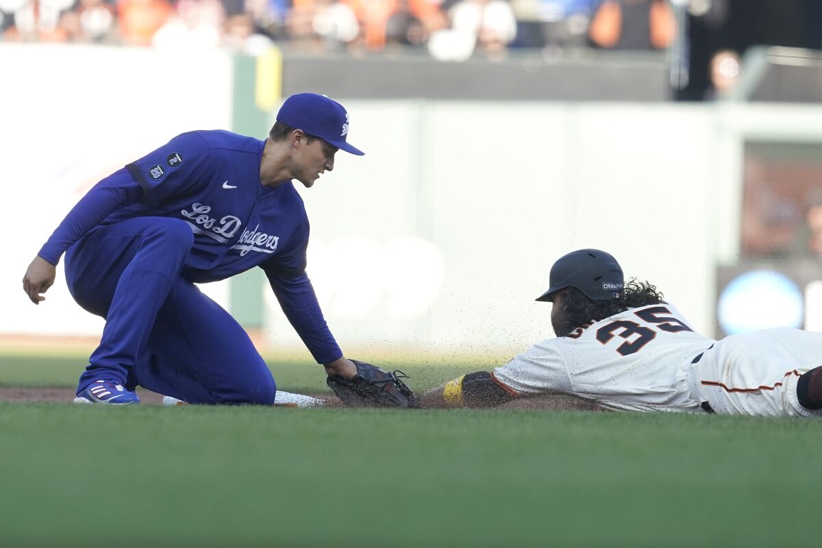 A Dodgers player tags a Giants player sliding head first