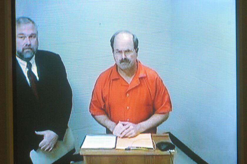 WICHITA, KS - MARCH 1: Serial murder suspect Dennis Rader (C) appears on a video screen as he makes his first court appearance, via video feed from the Sedgwick County Jail, before Judge Gregory Waller March 1, 2005 in Wichita, Kansas. At left is attorney Richard Ney. Rader, the man police have accused of being the B.T.K. serial killer, was charged with 10 counts of first degree murder. (Photo by Travis Heying-Pool/Getty Images) *** Local Caption *** Dennis Rader;Richard Ney ORG XMIT: 52242103