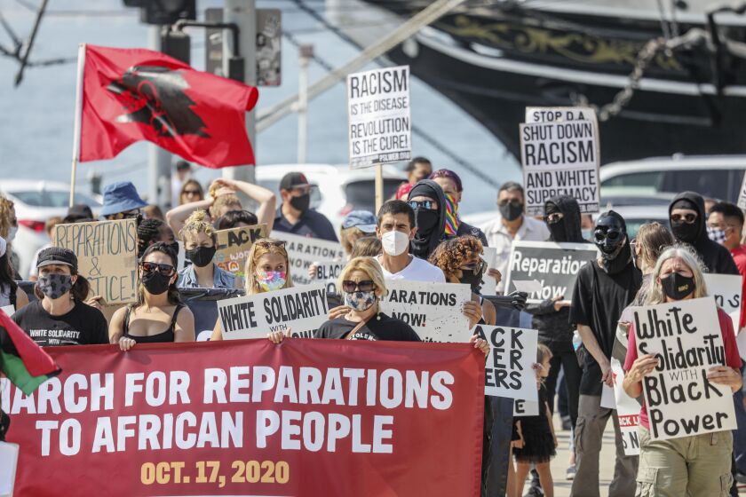 Marchers walk in downtown San Diego during the "March for Reparations to African People"which is a national day of political action coordinated by the Uhuru Solidarity Movement on Saturday, October 17, 2020.(Photo by Sandy Huffaker for The San Diego Union-Tribune)