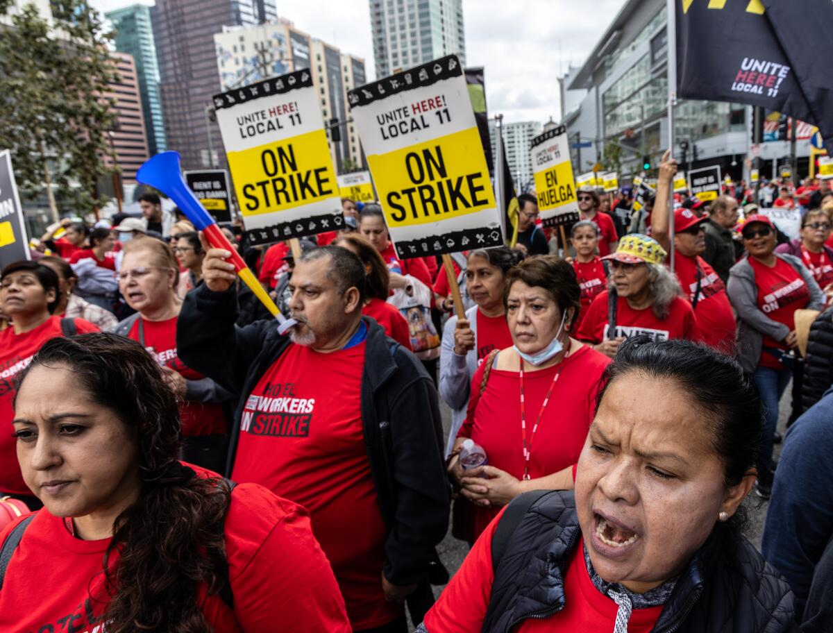 Strikers wearing read hold signs as they march down a city street.