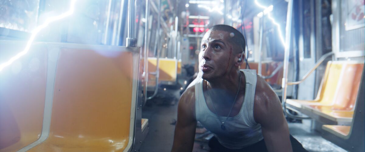 A man covered in sweat squats down in a subway train filled with electric bolts 