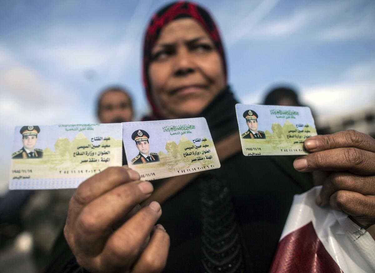 An Egyptian woman shows replica IDs with a portrait of Egypt's military commander Abdel Fattah Sisi.