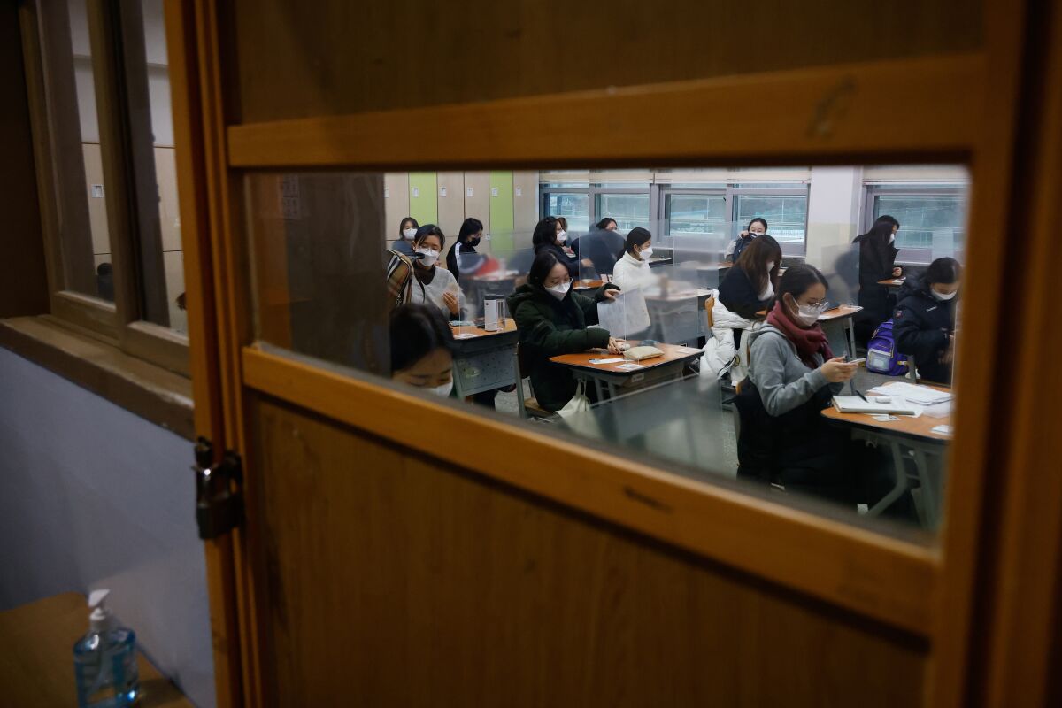 Students wearing face masks wait for the start of college entrance examination at an exam hall in Seoul.