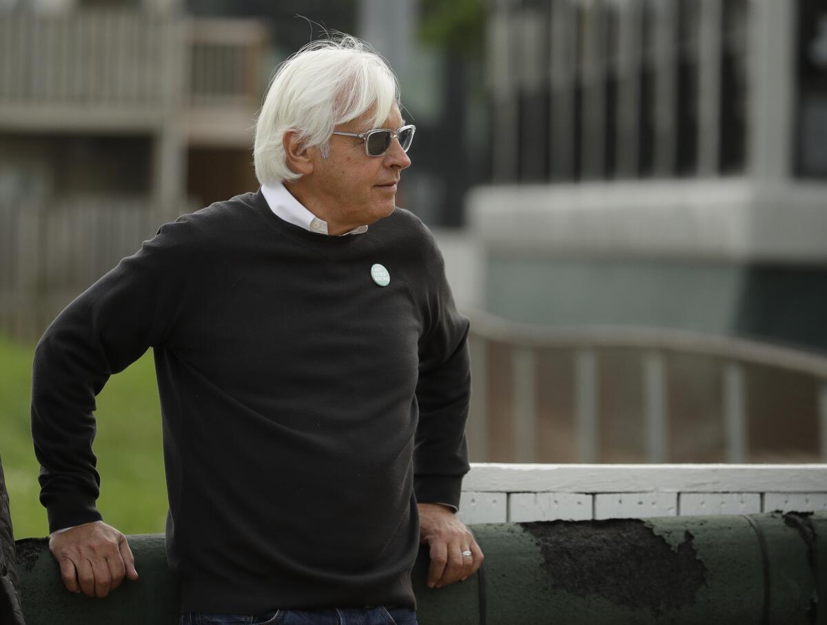 Horse trainer Bob Baffert leans against a barrier at Churchill Downs.