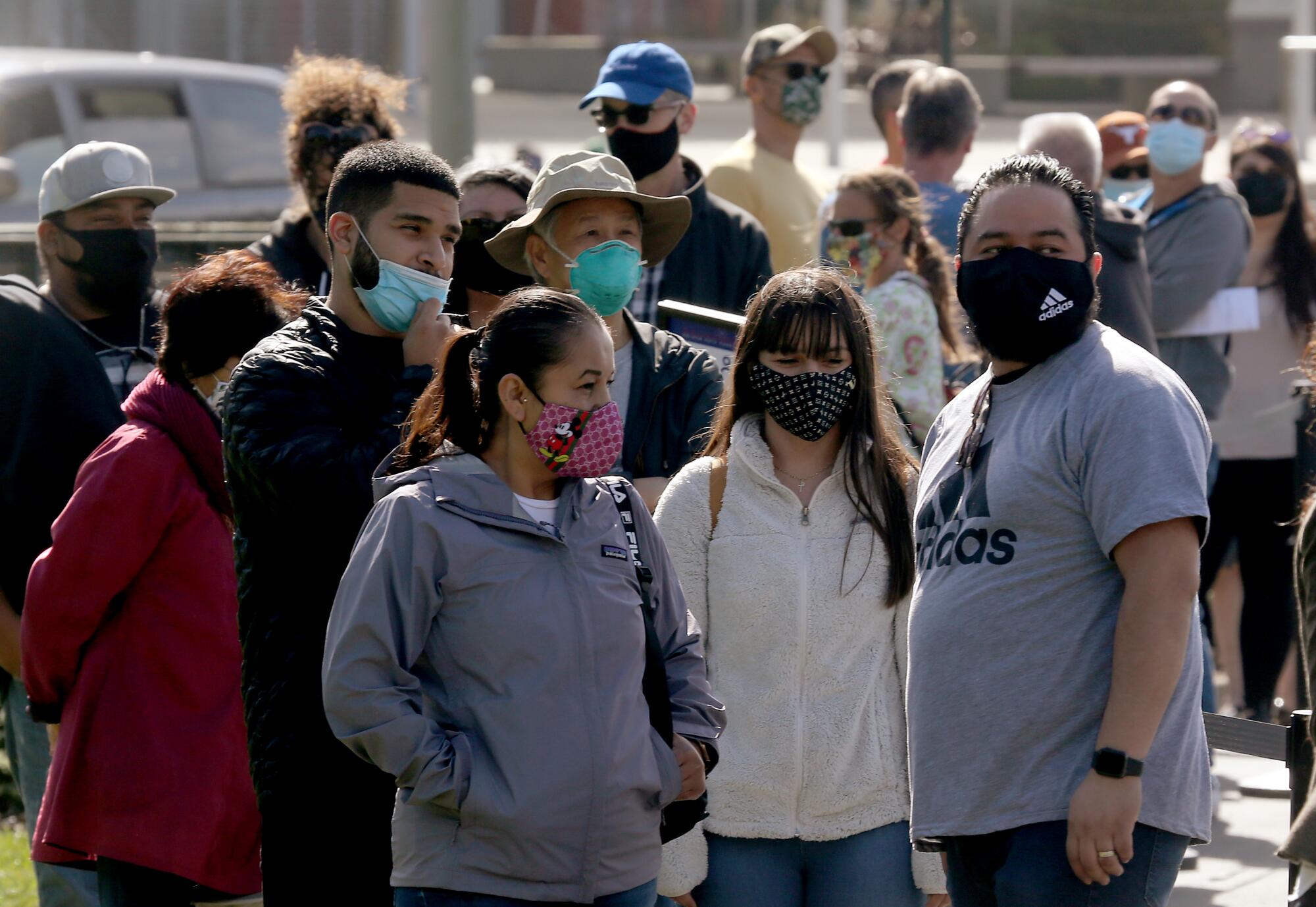 People wearing masks wait to ride the SkyStar Wheel, the Ferris wheel at Golden Gate Park in San Francisco.