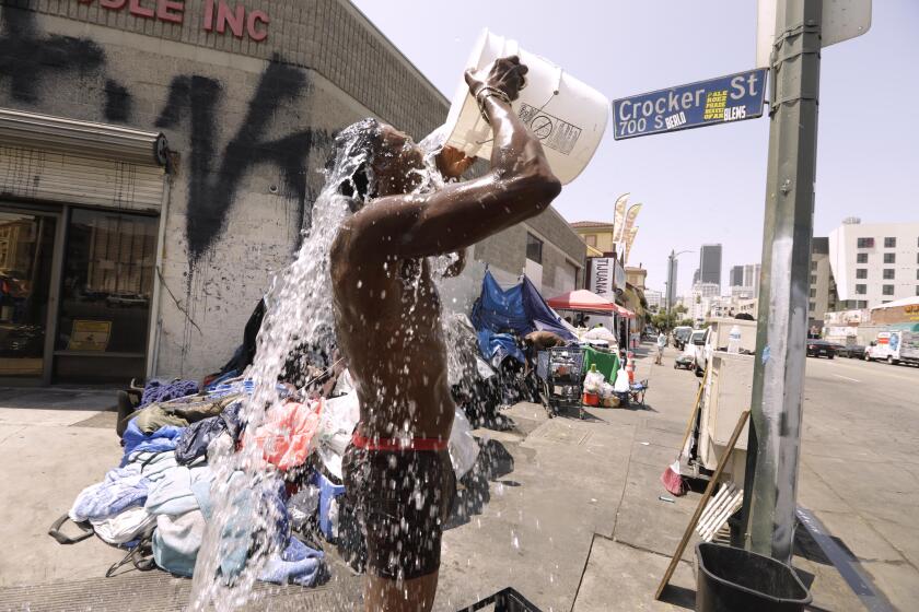Dennis Johnson, 60, pours water over himself as the temperature reaches 92 degrees on skid row in downtown Los Angeles.