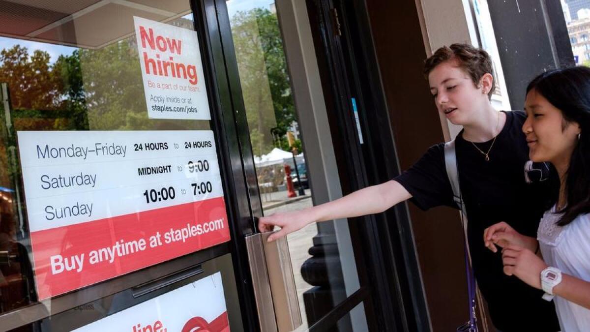A "now hiring" sign is displayed on the front entrance to a Staples store in New York City on June 2.