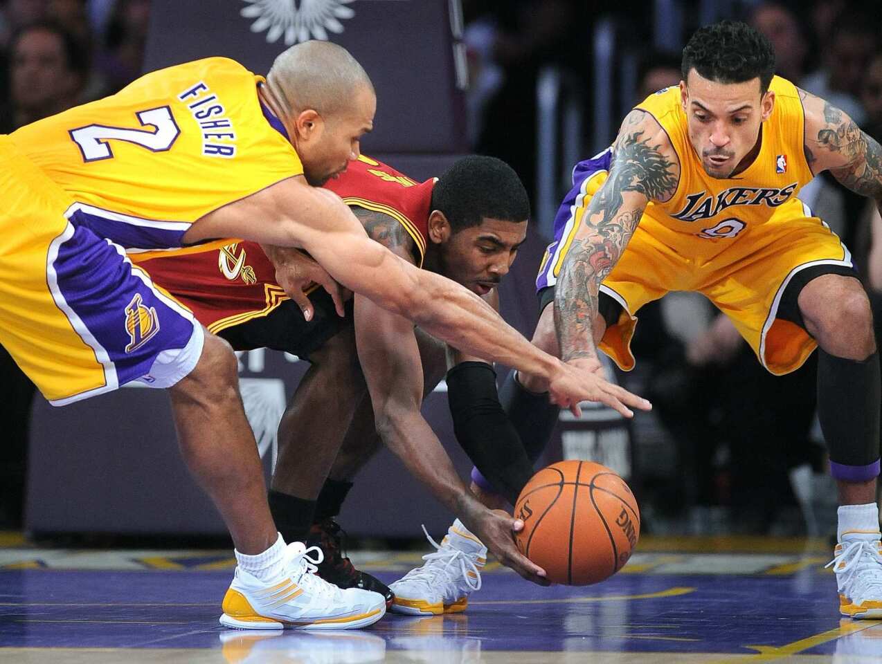 Cavaliers rookie point guard Kyrie Irving battles Lakers point guard Derek Fisher and forward Matt Barnes for a loose ball during the game Friday night at Staples Center.