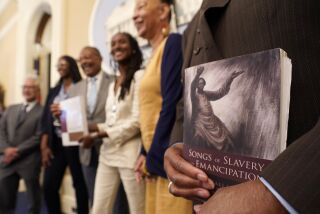 FILE — Dr. Amos C. Brown, Jr., vice chair for the California Reparations Task Force, right, holds a copy of the book Songs of Slavery and Emancipation, as he and other members of the task force pose for photos at the Capitol in Sacramento, Calif., on June 16, 2022. Economists for a California reparations task force estimate the state owes Black residents at least $800 billion for harms in policing, housing and health. The preliminary estimate will be discussed at the Wednesday, March 29, 2023, meeting of the state reparations task force. (AP Photo/Rich Pedroncelli, File)