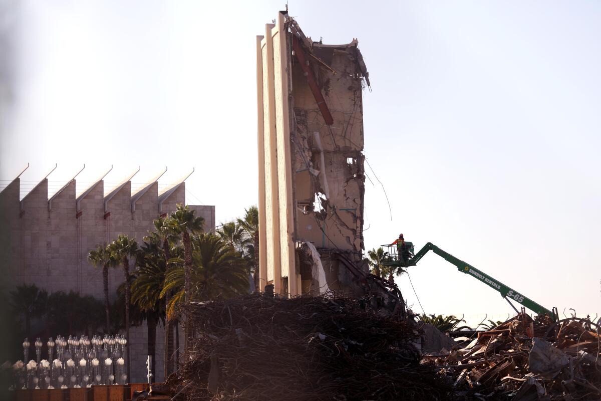 A construction worker in a lift rests next to some of the last remnants of the William Pereira-designed buildings at LACMA.