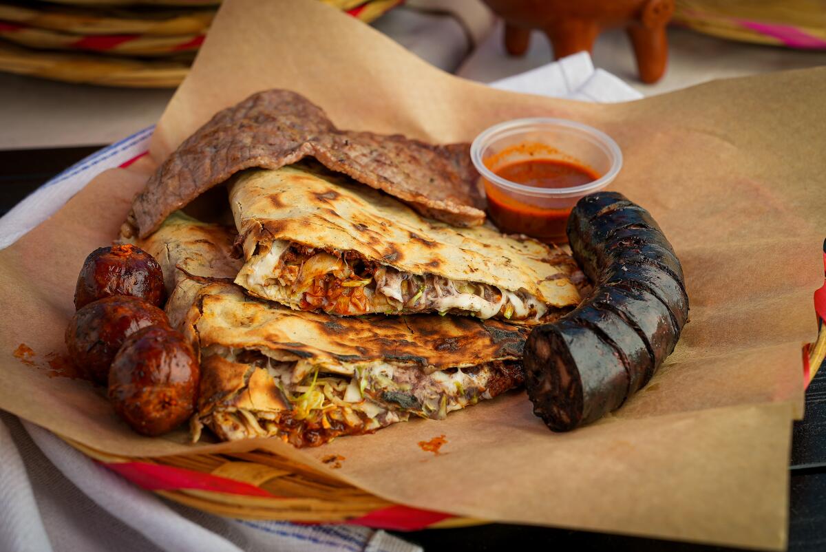 Piled-up sections of a folded tlayuda accompanied by pieces of meat