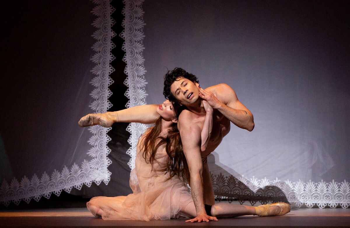Male and female ballet dancers entwined onstage.