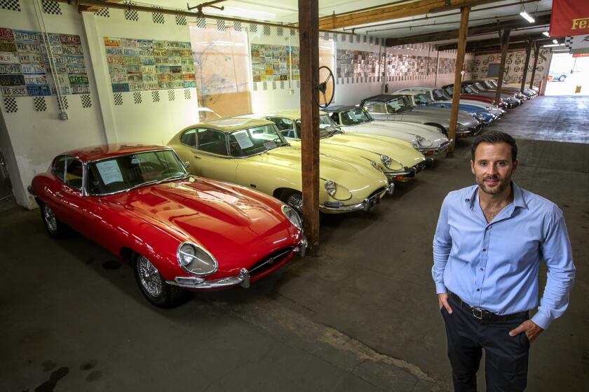 LOS ANGELES, CA-JUNE 29, 2022: Beverly Hills Car Club owner Alex Manos is photographed in the Jaguar section of his classic car dealership in Los Angeles. At left is a 1965 Jaguar XKE. (Mel Melcon / Los Angeles Times)