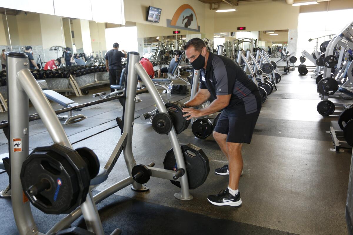 Andrew Dewey makes sure weights are properly stored on the first day 24-Hour Fitness reopened
