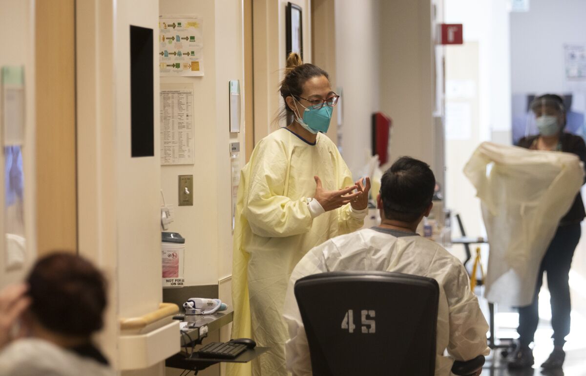 A woman in protective gear speaks to others inside a hospital.