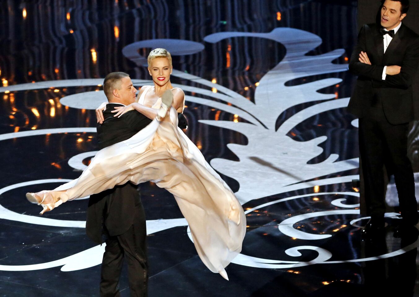 Channing Tatum dances with actress Charlize Theron as host Seth MacFarlane looks on during the 85th Academy Awards at the Dolby Theatre.